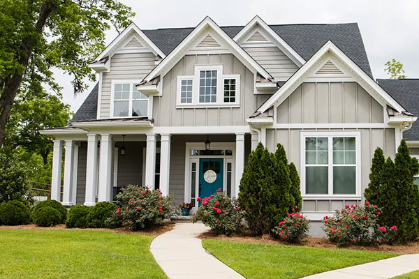 A two-story residential home with white trim, a well-kept lawn, and small porch